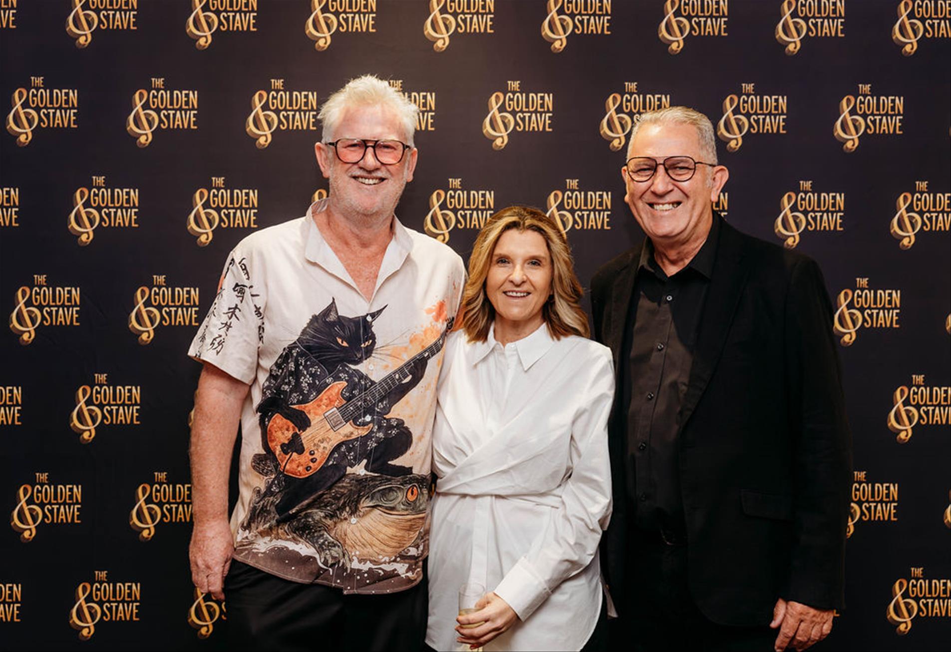 Three luncheon guests in front of the Golden Stave backdrop
